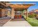 Backyard with a pergola-covered hot tub, artificial grass, and a covered patio at 7413 W Southgate Ave, Phoenix, AZ 85043
