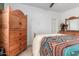 This bedroom features a bed dressed with a colorful blanket, ceiling fan, and natural wood dresser at 7413 W Southgate Ave, Phoenix, AZ 85043