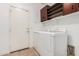 Bright laundry room featuring a washer and dryer, white cabinets, and a white door at 7413 W Southgate Ave, Phoenix, AZ 85043