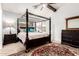 This spacious main bedroom features a four-poster bed, ceiling fan, and a dresser with a coordinating mirror at 7413 W Southgate Ave, Phoenix, AZ 85043