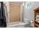 Cozy bathroom features a tiled shower, modern toilet, and convenient wooden shelf for storage at 7730 E Culver St, Mesa, AZ 85207