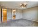 View of the main bedroom with doorways to bathroom and hallway, featuring a ceiling fan and gray carpeting at 1101 W Oleander Ave, Queen Creek, AZ 85140