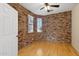Bedroom with brick accent wall, wood flooring, and a ceiling fan creates a cozy atmosphere at 1506 E Branham Ln, Phoenix, AZ 85042