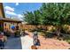 Landscaped backyard featuring a covered patio, lush garden, and a barbecue grill, ideal for outdoor entertaining at 16833 N 113Th Ave, Surprise, AZ 85378