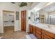 Bathroom featuring double sinks, wood cabinets, and a walk-in closet, perfect for storage and grooming at 18089 W Weatherby Dr, Surprise, AZ 85374