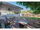 Comfortable, covered patio with a ceiling fan and gas grill overlooking a backyard with lush greenery and a producing fruit tree at 1909 E Bethany Home Rd, Phoenix, AZ 85016