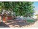 Backyard with mature shade trees and a brick home exterior, creating a cool and inviting outdoor environment at 1909 E Bethany Home Rd, Phoenix, AZ 85016