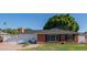 Charming brick home with a well-maintained lawn, a black roof, a brick chimney and a cozy front entrance with chairs at 1909 E Bethany Home Rd, Phoenix, AZ 85016