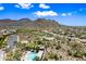 Scenic aerial view of the neighborhood, lush desert landscaping, a sparkling blue pool, and mountain views at 2638 W Sat Nam Way, Phoenix, AZ 85086