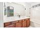 Bathroom featuring double sinks, a large mirror, vanity lighting, and a tub with shower at 2638 W Sat Nam Way, Phoenix, AZ 85086