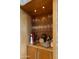 A close up of the wet bar featuring custom wood cabinetry, stone countertops, and glass shelving at 30600 N Pima Rd # 61, Scottsdale, AZ 85266
