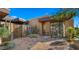 A stone-paved walkway leads to the modern desert home with a wooden gate and manicured succulents at 30600 N Pima Rd # 61, Scottsdale, AZ 85266