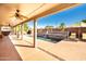 Covered back patio with ceiling fans overlooking a luxurious pool with a stone water feature and lush greenery at 3597 W Mineral Butte Dr, San Tan Valley, AZ 85144