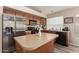 Well-equipped kitchen boasts stainless steel appliances, oak cabinets, a kitchen island, and wood-look vinyl flooring at 41280 W Sanders Way, Maricopa, AZ 85138