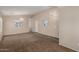 Bright and spacious living room featuring neutral walls, carpet and vinyl flooring, and decorative light fixtures at 41280 W Sanders Way, Maricopa, AZ 85138