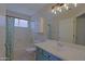 Bright bathroom featuring a blue vanity with a white sink, a tub with shower, and ample cabinet storage at 42812 W Venture Rd, Maricopa, AZ 85138