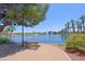 Scenic view of a lake with fountains, palm trees, and a shaded bench offering a tranquil spot at 42812 W Venture Rd, Maricopa, AZ 85138