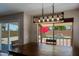 Dining area with rustic table, modern chandelier, and sliding glass door to the pool area at 42812 W Venture Rd, Maricopa, AZ 85138