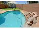 Sparkling pool with waterfall feature and basketball hoop in a landscaped backyard at 42812 W Venture Rd, Maricopa, AZ 85138