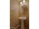 Elegant powder room with pedestal sink, decorative wallpaper, and updated lighting at 42812 W Venture Rd, Maricopa, AZ 85138