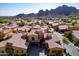 An aerial view of desert townhouses with terracotta tile roofs, mountain views, and well manicured streetscapes at 5370 S Desert Dawn Dr # 56, Gold Canyon, AZ 85118