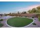 Lush backyard featuring a manicured lawn, gravel landscaping, fire pit, and outdoor kitchen for relaxation and entertainment at 7415 W Lisbon Ln, Peoria, AZ 85381
