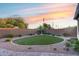 Beautiful backyard featuring a putting green, desert landscaping, and a privacy wall with a stunning sunset at 7415 W Lisbon Ln, Peoria, AZ 85381