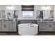 Bright bathroom featuring a soaking tub, double vanities with gray cabinets and modern fixtures, and a view from a window at 7415 W Lisbon Ln, Peoria, AZ 85381