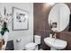 Stylish powder room featuring a pedestal sink, decorative mirror, modern fixtures, and elegant decor at 7415 W Lisbon Ln, Peoria, AZ 85381
