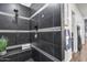 Modern black tiled shower with a bench, rainfall shower head, and a built-in niche for toiletries at 7415 W Lisbon Ln, Peoria, AZ 85381