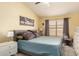 Cozy bedroom with a queen-sized bed, ceiling fan, and a large window offering natural light at 8319 E Portobello Ave, Mesa, AZ 85212