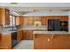 Well-appointed kitchen with granite counters, wood cabinets, and modern black appliances at 8511 W Via Montoya Dr, Peoria, AZ 85383