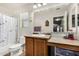 Bright bathroom featuring a shower-tub combo, toilet, and single sink vanity with warm-toned cabinets at 942 S Deerfield Ln, Gilbert, AZ 85296