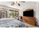 Spacious bedroom features a ceiling fan, dresser with TV and a bright window seat filled with plants at 942 S Deerfield Ln, Gilbert, AZ 85296