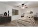 This bedroom features neutral décor, a ceiling fan, and a bright window for a cozy retreat at 12132 W Caribbean Ln, El Mirage, AZ 85335