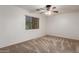 This bedroom has carpet flooring, a ceiling fan, and a bright window for a cozy relaxation space at 12132 W Caribbean Ln, El Mirage, AZ 85335
