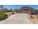 Spacious driveway leading to a beige home with a two-car garage and desert landscaping at 12132 W Caribbean Ln, El Mirage, AZ 85335
