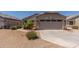Tan home featuring a two-car garage and desert landscaping at 12132 W Caribbean Ln, El Mirage, AZ 85335