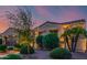 A beautifully landscaped home featuring desert plants and trees under a vivid sunset sky at 13716 W Nogales Dr, Sun City West, AZ 85375