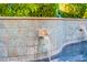 Close up of a tiled water feature flowing into a sparkling pool at 13716 W Nogales Dr, Sun City West, AZ 85375