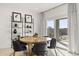 Bright dining area featuring a modern round table with black chairs, next to a sliding glass door and decorative shelves at 15348 W Gray Fox Trl, Surprise, AZ 85387