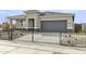 Inviting home exterior with a two-car garage, featuring manicured landscaping enclosed by a sleek black metal fence at 15348 W Gray Fox Trl, Surprise, AZ 85387