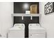 Convenient laundry room with white washer and dryer, shelf, and modern decor at 15348 W Gray Fox Trl, Surprise, AZ 85387