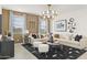 Comfortable living room with a large sectional sofa, stylish chandelier, and striking black and white rug at 15348 W Gray Fox Trl, Surprise, AZ 85387