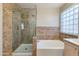 Modern bathroom featuring separate glass-enclosed shower and luxurious soaking tub with natural light from a glass block window at 18207 N 46Th St, Phoenix, AZ 85032