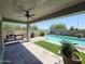 Covered patio with ceiling fan and built-in barbeque, with a view of the sparkling pool and landscaped yard at 18871 S 209Th Way, Queen Creek, AZ 85142