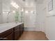 Well-lit bathroom with dual sinks, a large mirror, and a bathtub with shower at 19771 W Woodlands Ave, Buckeye, AZ 85326