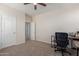 A home bedroom featuring neutral walls, carpeted floors, ceiling fan, and a workspace with desk and chair at 19771 W Woodlands Ave, Buckeye, AZ 85326