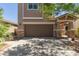 Two-story home showing a two-car garage, manicured landscape, and shade trees on a sunny day at 19771 W Woodlands Ave, Buckeye, AZ 85326