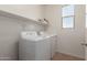 Functional laundry room with washer, dryer, storage shelf and natural light at 19771 W Woodlands Ave, Buckeye, AZ 85326
